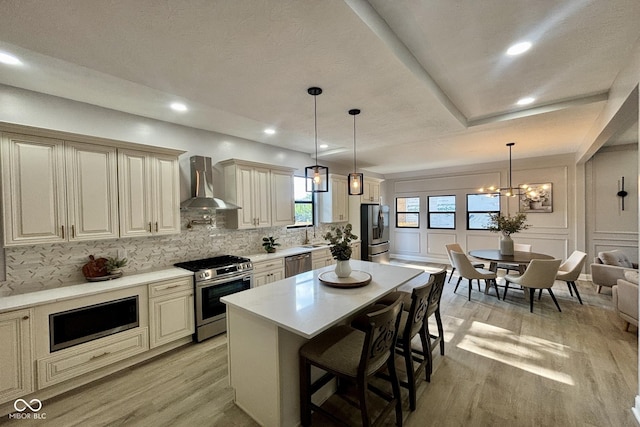 1440 S New Jersey St, Indianapolis, IN 46225 - kitchen featuring stainless steel appliances, wall chimney exhaust hood, cream cabinets, light wood-style floors, and recessed lighting