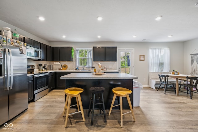 197 N Fairfield Dr, Danville, IN 46122 - kitchen featuring stainless steel appliances, light countertops, light wood-style flooring, a breakfast bar, and recessed lighting