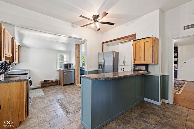631 S State Road 39, Danville, IN 46122 - kitchen featuring appliances with stainless steel finishes, a peninsula, dark countertops, ceiling fan, and stone finish flooring