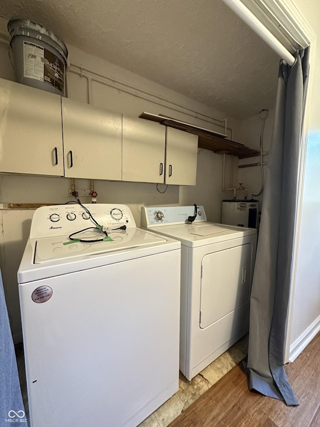 107 S Nebraska St, North Salem, IN 46165 - laundry area featuring washing machine and dryer, cabinet space, electric water heater, light wood-style floors, and a textured ceiling