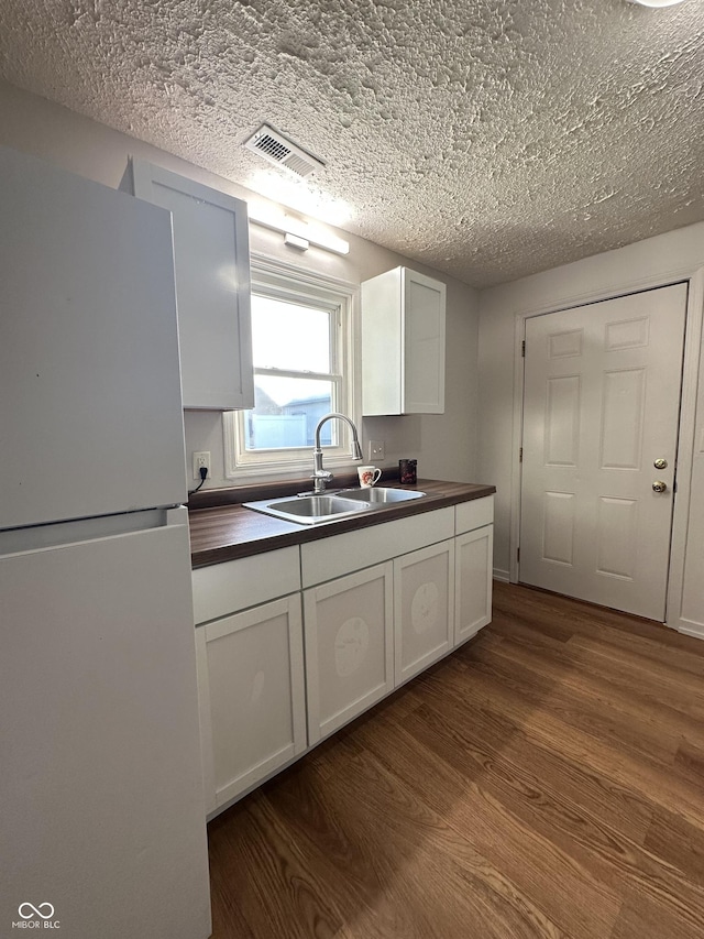 107 S Nebraska St, North Salem, IN 46165 - kitchen with freestanding refrigerator, dark wood finished floors, a textured ceiling, white cabinets, and butcher block counters