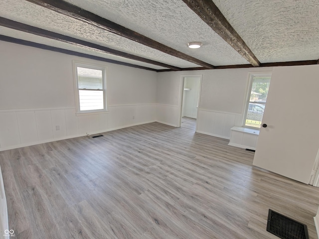 316 E Mechanic St, Shelbyville, IN 46176 - empty room featuring beam ceiling, healthy amount of natural light, wainscoting, light wood-type flooring, and a textured ceiling