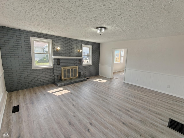 316 E Mechanic St, Shelbyville, IN 46176 - unfurnished living room featuring a textured ceiling, wood finished floors, brick wall, a fireplace, and wainscoting