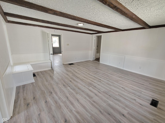 316 E Mechanic St, Shelbyville, IN 46176 - unfurnished room featuring beam ceiling, wainscoting, light wood-style flooring, a decorative wall, and a textured ceiling