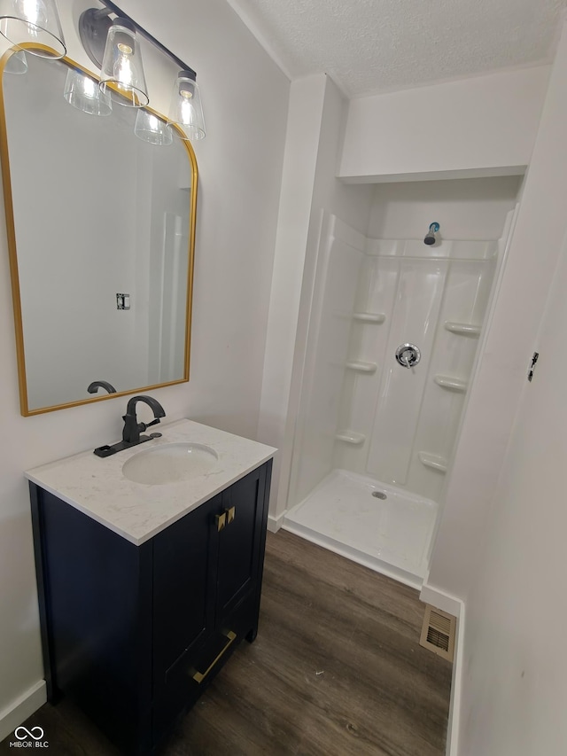 316 E Mechanic St, Shelbyville, IN 46176 - bathroom featuring wood finished floors, vanity, walk in shower, and a textured ceiling