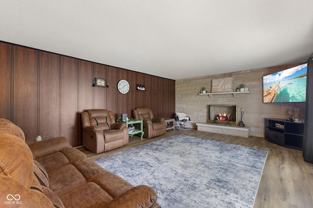 10816 N US Highway 231, Cloverdale, IN 46120 - living room featuring wood walls, light wood finished floors, a stone fireplace, and a textured ceiling