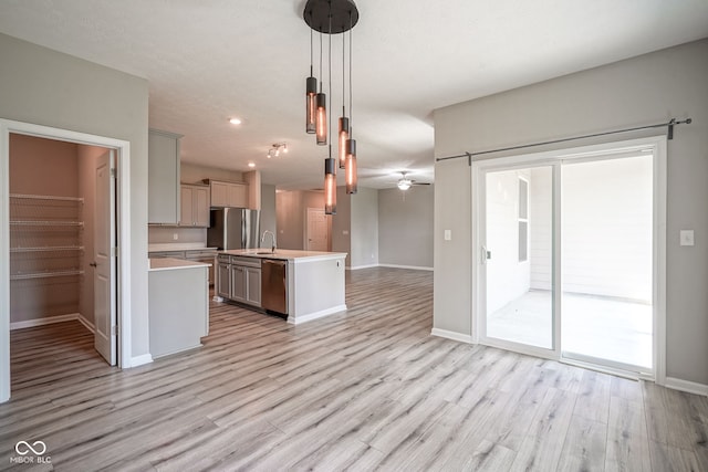 2541 Riviera Pl, Greenwood, IN 46143 - kitchen with appliances with stainless steel finishes, open floor plan, light countertops, light wood-style floors, and pendant lighting