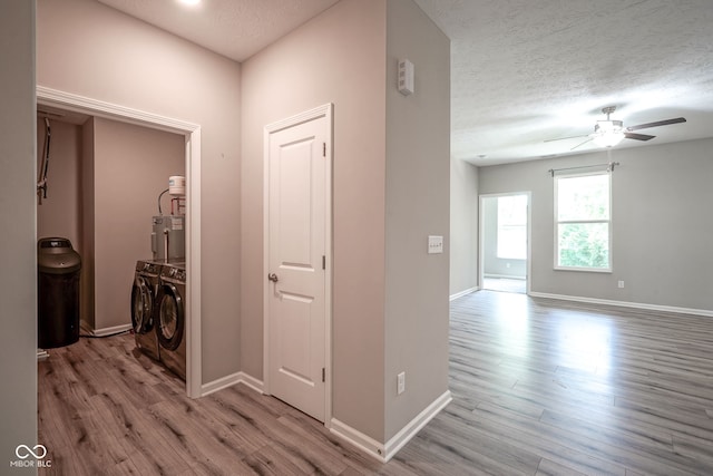 2541 Riviera Pl, Greenwood, IN 46143 - hall featuring independent washer and dryer, light wood-type flooring, water heater, and a textured ceiling