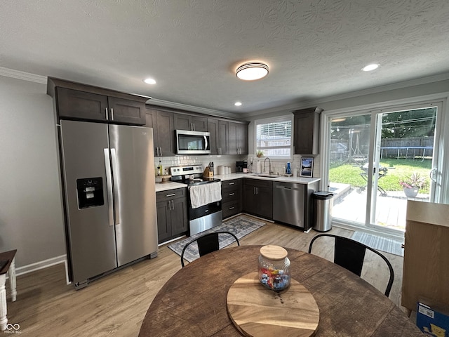 315 W N St, Crawfordsville, IN 47933 - kitchen with appliances with stainless steel finishes, crown molding, light wood-style flooring, light countertops, and backsplash