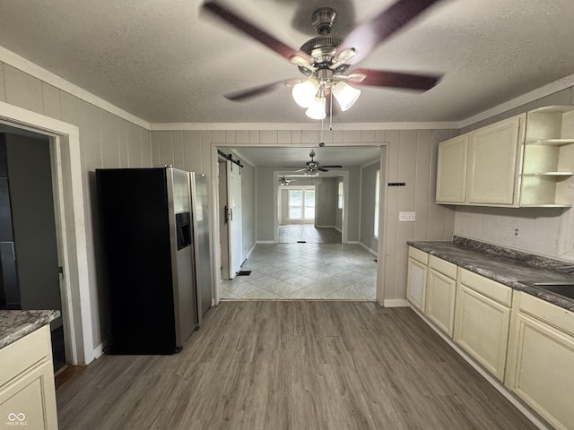 2002 N Audubon Rd, Indianapolis, IN 46218 - kitchen with stainless steel refrigerator with ice dispenser, open shelves, a ceiling fan, a barn door, and light wood finished floors