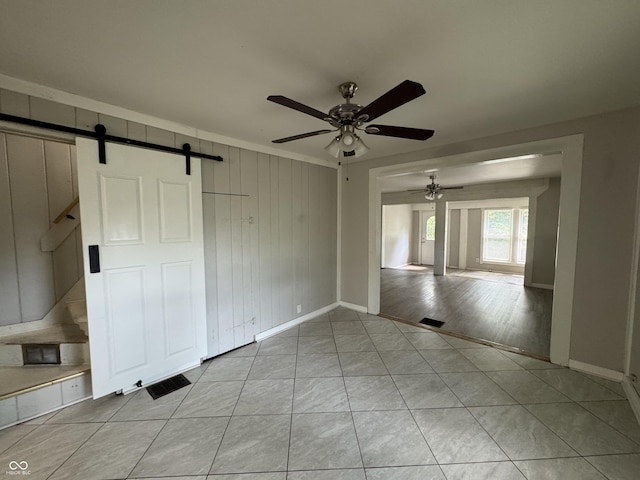 2002 N Audubon Rd, Indianapolis, IN 46218 - unfurnished room featuring a barn door, a ceiling fan, light tile patterned flooring, and wood walls