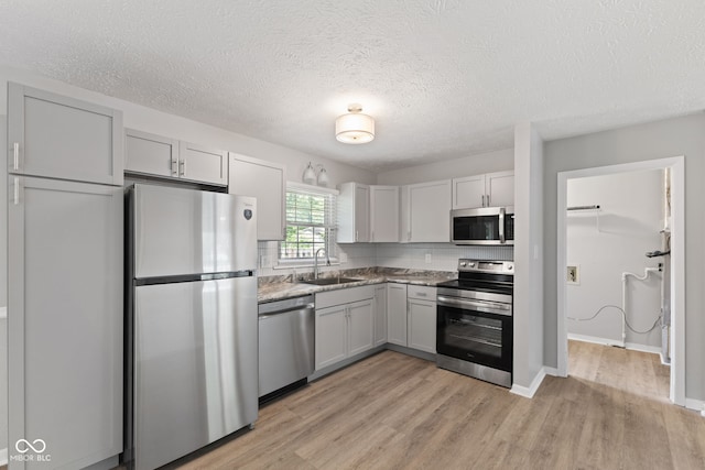 3102 Pawnee Dr, Indianapolis, IN 46235 - kitchen featuring appliances with stainless steel finishes, light wood-type flooring, gray cabinets, and a textured ceiling