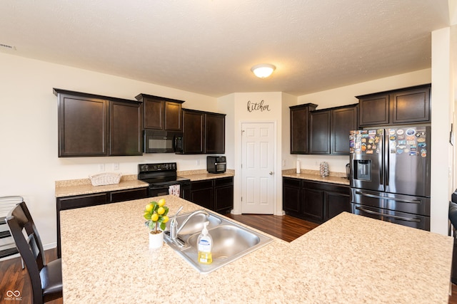 7626 Merrick Dr, Brownsburg, IN 46112 - kitchen featuring black appliances, dark brown cabinets, dark wood finished floors, light countertops, and a breakfast bar