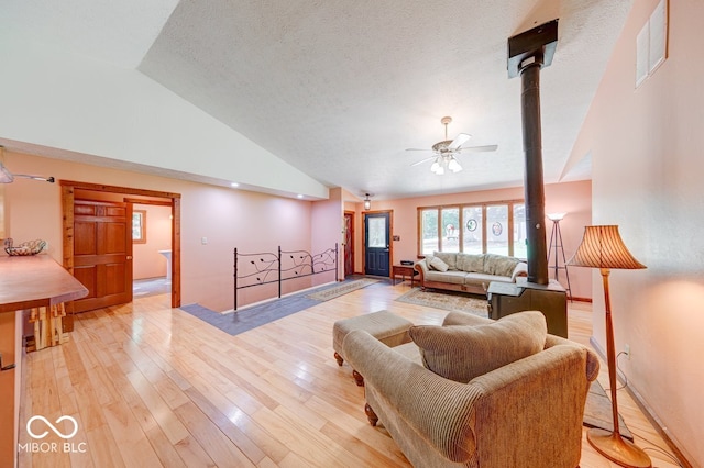 8910 Richarts Rd, Morgantown, IN 46160 - living room featuring vaulted ceiling, a ceiling fan, light wood-style flooring, a textured ceiling, and a wood stove