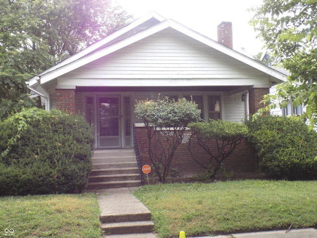 940 N Grant Ave, Indianapolis, IN 46201 - bungalow featuring a chimney, a front yard, and brick siding
