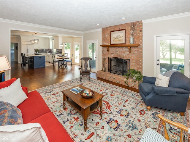8708 Highwood Ln, Indianapolis, IN 46278 - living room featuring dark wood finished floors, a brick fireplace, a textured ceiling, crown molding, and a chandelier