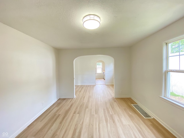 4002 E Pleasant Run Parkway N Drive, Indianapolis, IN 46201 - spare room featuring arched walkways, light wood-type flooring, and a textured ceiling