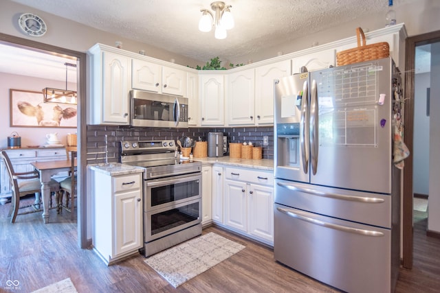 5237 Honey Comb Ln, Indianapolis, IN 46221 - kitchen featuring stainless steel appliances, white cabinetry, dark wood-style floors, tasteful backsplash, and a textured ceiling
