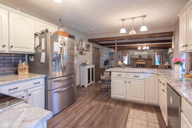 5237 Honey Comb Ln, Indianapolis, IN 46221 - kitchen with appliances with stainless steel finishes, dark wood-type flooring, white cabinets, a peninsula, and a brick fireplace