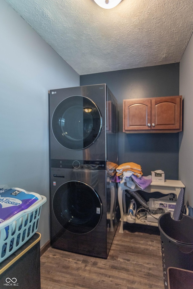 5237 Honey Comb Ln, Indianapolis, IN 46221 - laundry room featuring stacked washer and clothes dryer, cabinet space, wood finished floors, and a textured ceiling