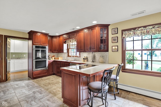 5238 N 225 E, Whiteland, IN 46184 - kitchen featuring stainless steel double oven, black electric stovetop, a baseboard heating unit, a peninsula, and glass insert cabinets