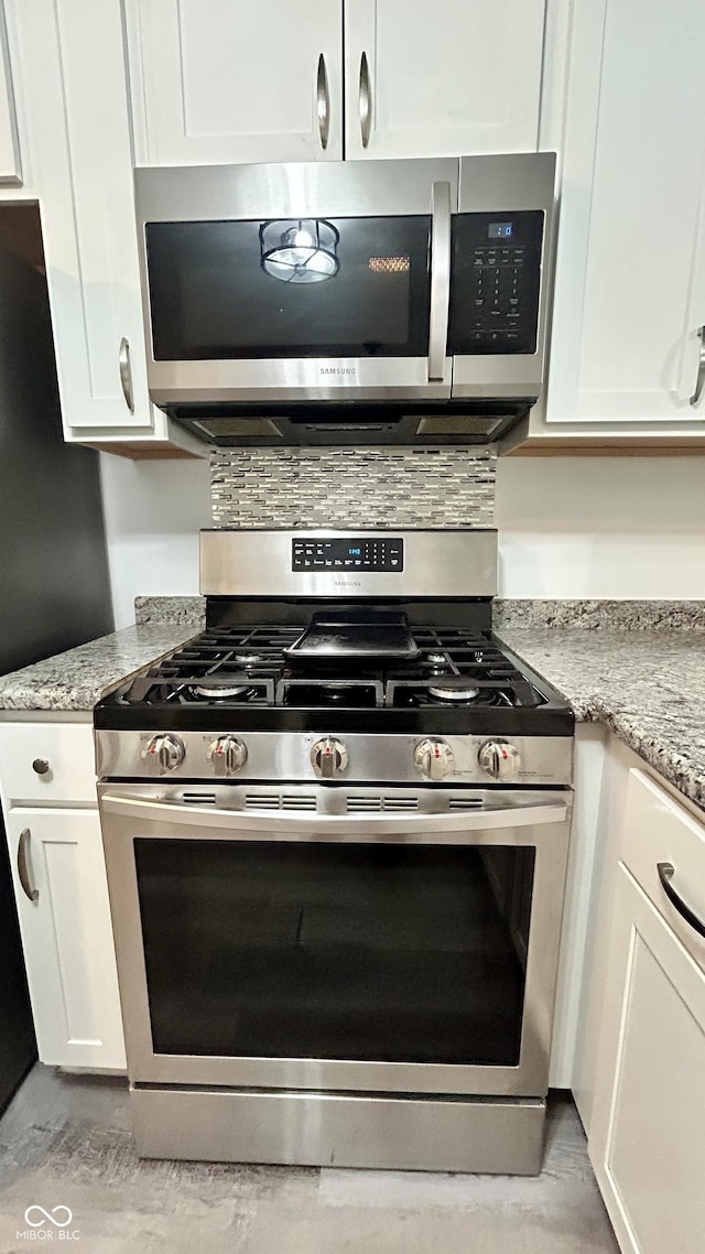 7231 S Franklin Rd, Indianapolis, IN 46259 - kitchen featuring appliances with stainless steel finishes, white cabinets, light stone counters, and tasteful backsplash