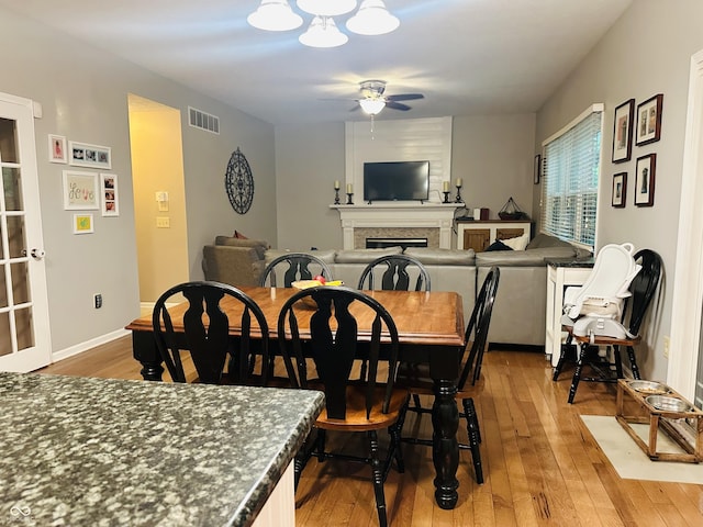 9975 Woodstock Way, Fishers, IN 46037 - dining space with ceiling fan, light wood-style flooring, and a large fireplace
