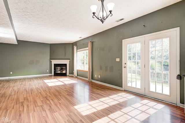 1143 Kinross Dr, Avon, IN 46123 - unfurnished living room featuring wood finished floors, a textured ceiling, a chandelier, and a fireplace with flush hearth