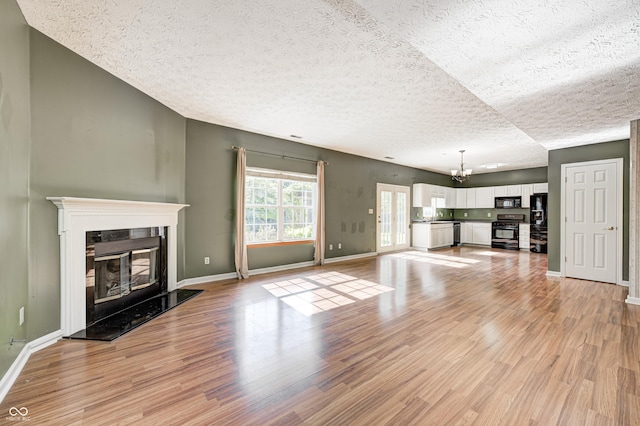 1143 Kinross Dr, Avon, IN 46123 - unfurnished living room with a textured ceiling, light wood-style floors, a chandelier, and a glass covered fireplace