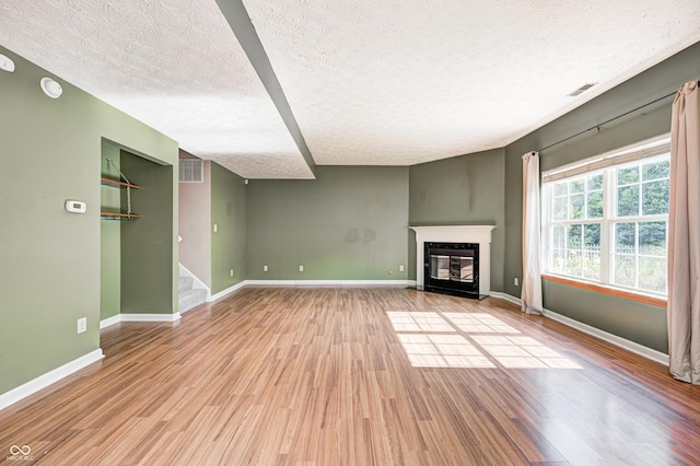 1143 Kinross Dr, Avon, IN 46123 - unfurnished living room with a textured ceiling, wood finished floors, a fireplace with flush hearth, and stairway