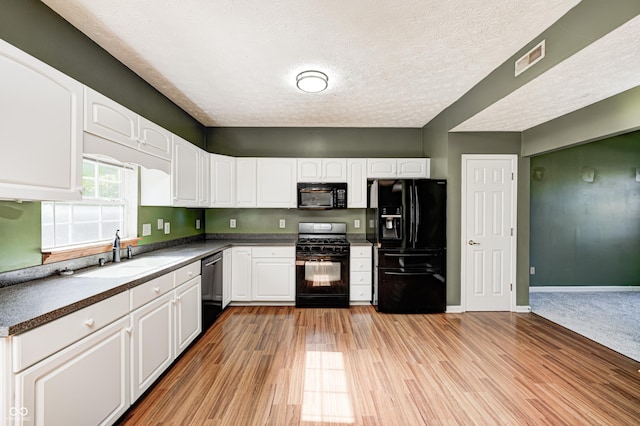 1143 Kinross Dr, Avon, IN 46123 - kitchen featuring black appliances, white cabinets, light wood-style flooring, a textured ceiling, and dark countertops