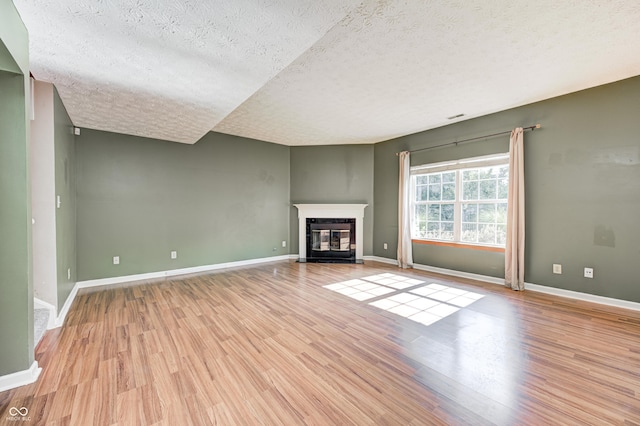 1143 Kinross Dr, Avon, IN 46123 - unfurnished living room with a textured ceiling, light wood-style flooring, and a fireplace with flush hearth