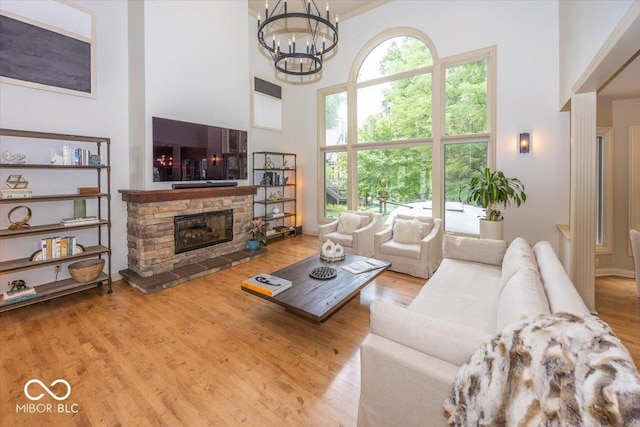 13023 Water Ridge Dr, Mccordsville, IN 46055 - living room with a high ceiling, a stone fireplace, a chandelier, and wood finished floors
