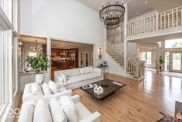 13023 Water Ridge Dr, Mccordsville, IN 46055 - living room featuring a chandelier, stairs, a towering ceiling, and wood finished floors