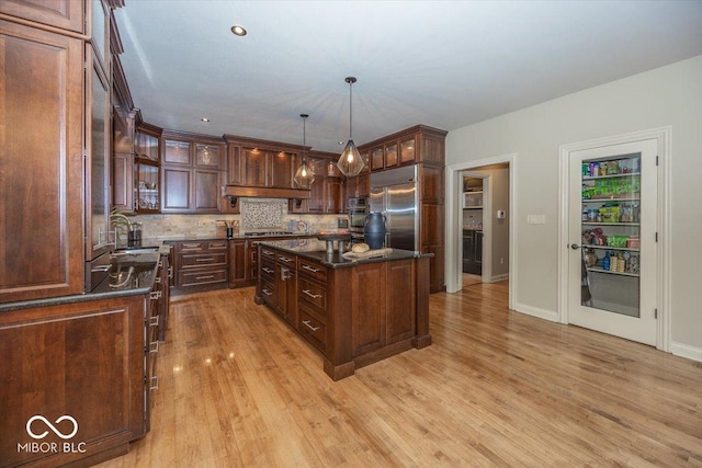 13023 Water Ridge Dr, Mccordsville, IN 46055 - kitchen featuring stainless steel appliances, light wood-style flooring, decorative backsplash, glass insert cabinets, and decorative light fixtures