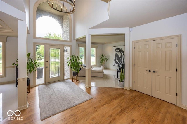 13023 Water Ridge Dr, Mccordsville, IN 46055 - entrance foyer with light wood-style floors, decorative columns, a chandelier, and a towering ceiling