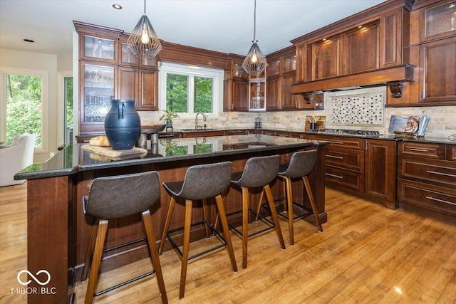 13023 Water Ridge Dr, Mccordsville, IN 46055 - kitchen with light wood-type flooring, tasteful backsplash, hanging light fixtures, and stainless steel gas cooktop