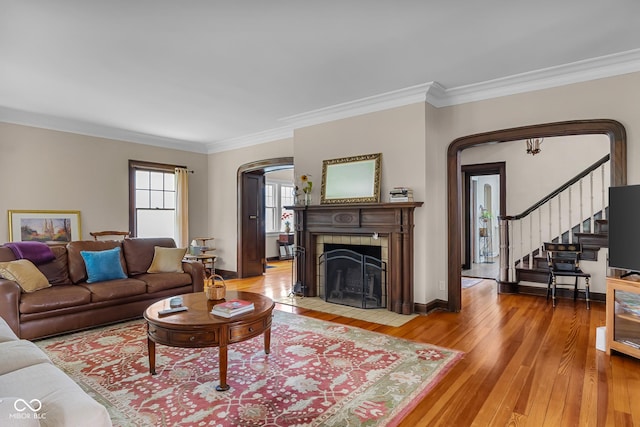 613 5th St, Columbus, IN 47201 - living area featuring arched walkways, light wood finished floors, crown molding, stairway, and a tiled fireplace