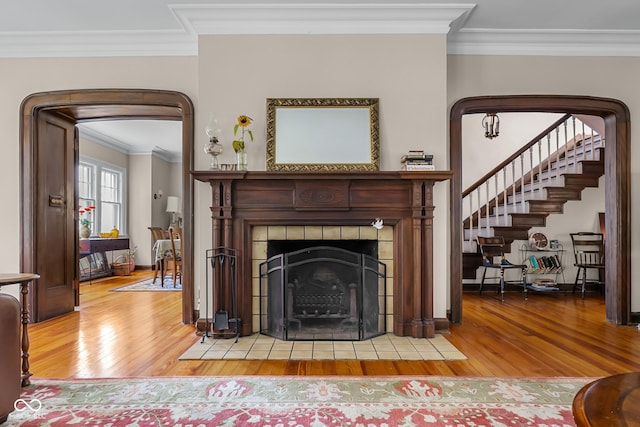 613 5th St, Columbus, IN 47201 - living room with hardwood / wood-style floors, arched walkways, a tile fireplace, crown molding, and stairs