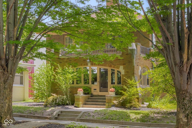 613 5th St, Columbus, IN 47201 - view of front facade featuring a balcony, brick siding, entry steps, and a chimney