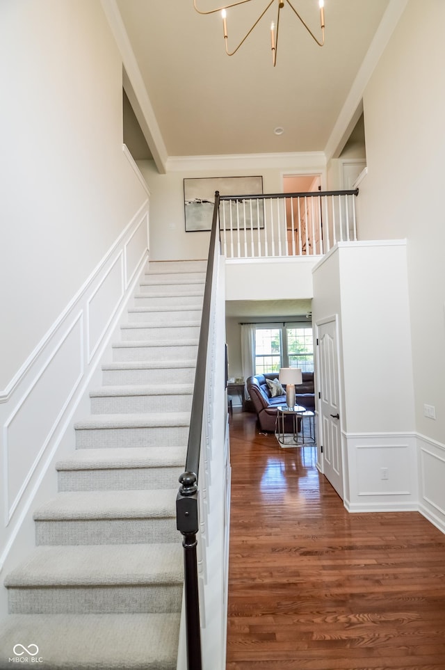 6802 Chorleywood Cir, Indianapolis, IN 46259 - stairway featuring a decorative wall, a chandelier, wood finished floors, wainscoting, and crown molding