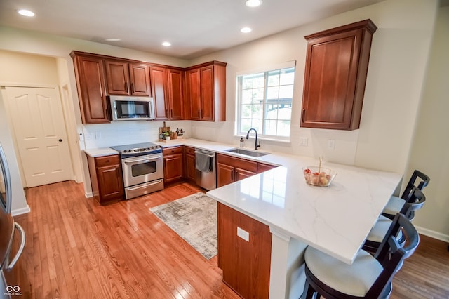 6802 Chorleywood Cir, Indianapolis, IN 46259 - kitchen with stainless steel appliances, a peninsula, light wood-type flooring, a breakfast bar, and recessed lighting