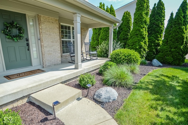 6802 Chorleywood Cir, Indianapolis, IN 46259 - view of exterior entry with covered porch, brick siding, and a lawn