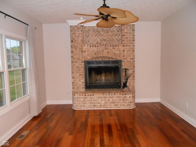 7653 W Old Colony Dr, New Palestine, IN 46163 - unfurnished living room with wood finished floors, a brick fireplace, a ceiling fan, and a textured ceiling