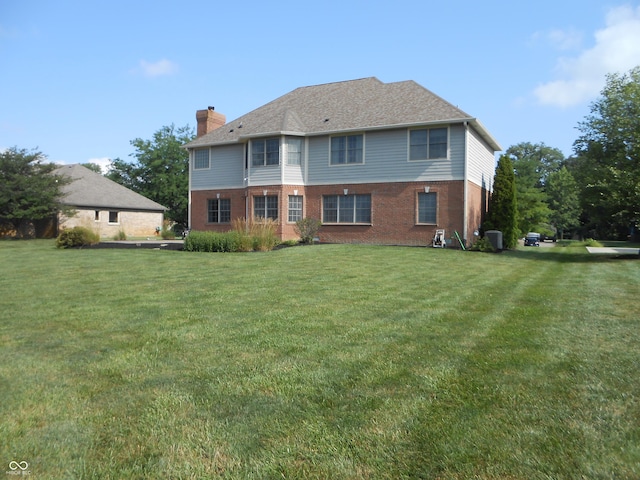 7653 W Old Colony Dr, New Palestine, IN 46163 - rear view of property with brick siding, a chimney, and a lawn