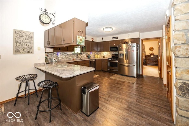 8546 N Chickadee Dr, Morgantown, IN 46160 - kitchen featuring stainless steel appliances, a peninsula, backsplash, dark wood finished floors, and a breakfast bar area