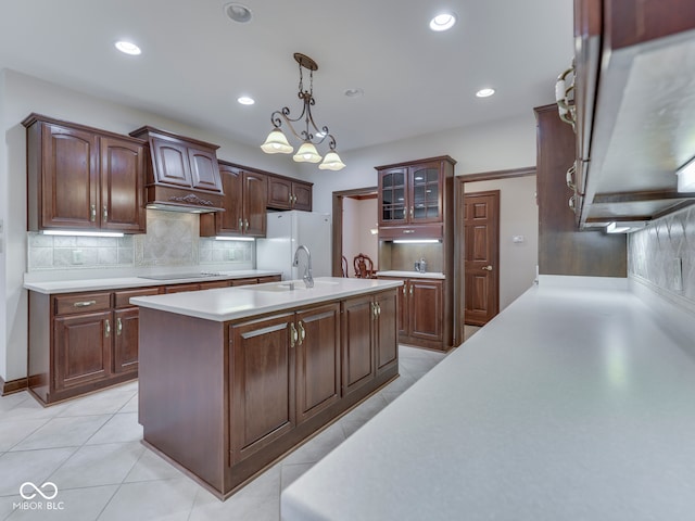 2025 Caledonian Ct, Greenwood, IN 46143 - kitchen featuring light countertops, decorative backsplash, glass insert cabinets, pendant lighting, and a kitchen island with sink