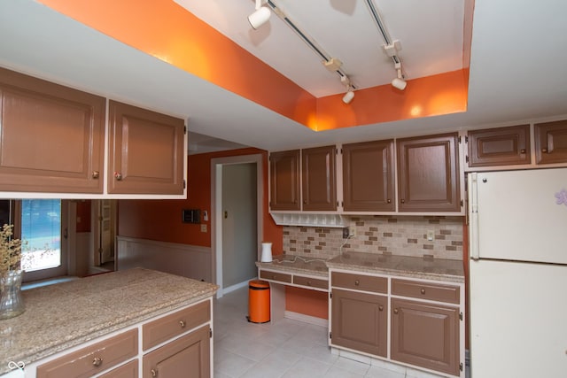 8841 Rocky Ridge Rd, Indianapolis, IN 46217 - kitchen featuring freestanding refrigerator, light tile patterned flooring, backsplash, track lighting, and a tray ceiling