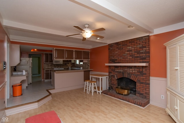 8841 Rocky Ridge Rd, Indianapolis, IN 46217 - living area featuring ceiling fan, light wood finished floors, a brick fireplace, and a wainscoted wall