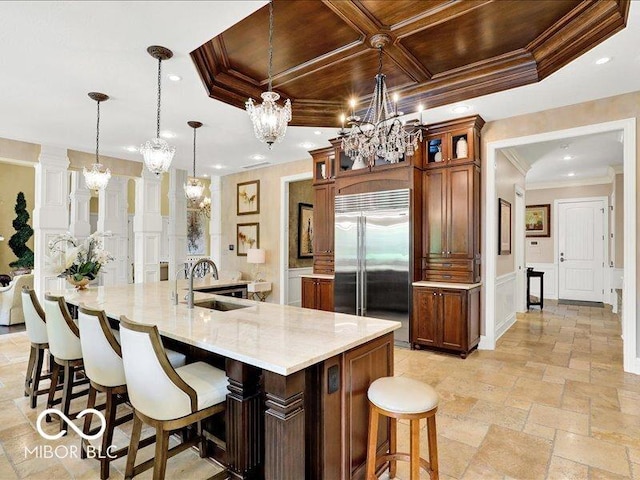 3808 Claybrook Ct, Bargersville, IN 46106 - kitchen featuring stainless steel built in refrigerator, a chandelier, ornamental molding, a decorative wall, and a kitchen bar